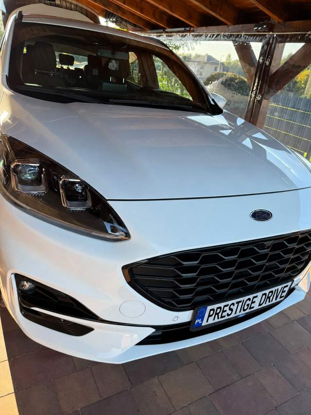 Biały Ford na stanowisku pod zadaszeniem, widok od przodu.